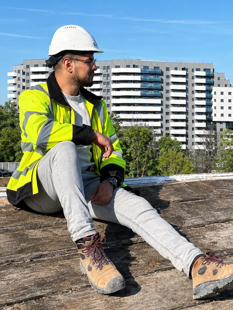 Rabie Khafifi sur le toit d'un bâtiment en chantier à Bucarest, casque de sécurité sur la tête